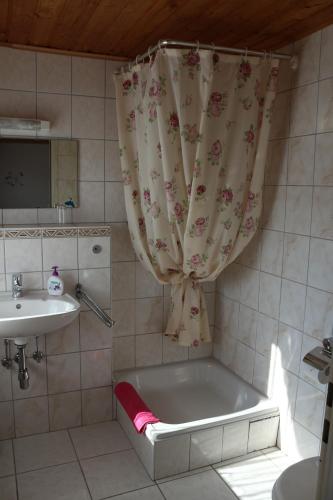 ein Badezimmer mit einer Badewanne, einem Waschbecken und einem Duschvorhang in der Unterkunft Pension Fernblick in Bad Karlshafen