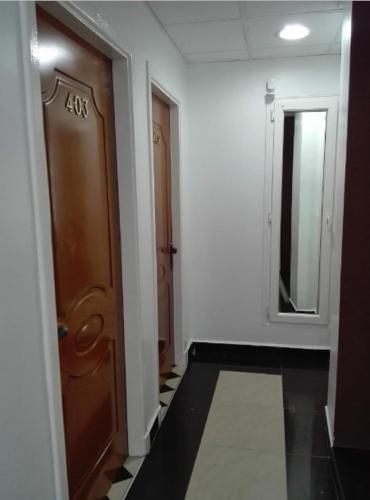 a hallway with a wooden door and a mirror at LES 2 HORLOGES in Oran
