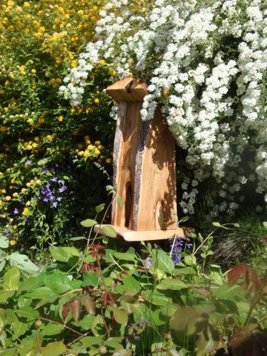 a wooden bird house in a garden with flowers at Residence Obermoarhof - Family Apartments with Pool & Playground in Vandoies