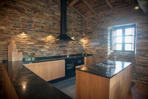 a kitchen with a counter and a stone wall at Aldea Rural y Gastro Restaurante Casona de Labrada in Labrada