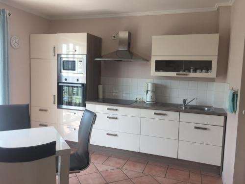 a kitchen with white cabinets and a sink and a table at Strandvilla Kalifornien direkt am Meer in Kalifornien