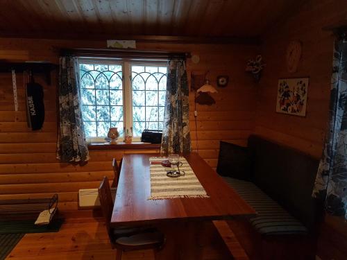 Un comedor con una mesa de madera y una ventana. en Liten timmerstuga i Sälen, en Sälen