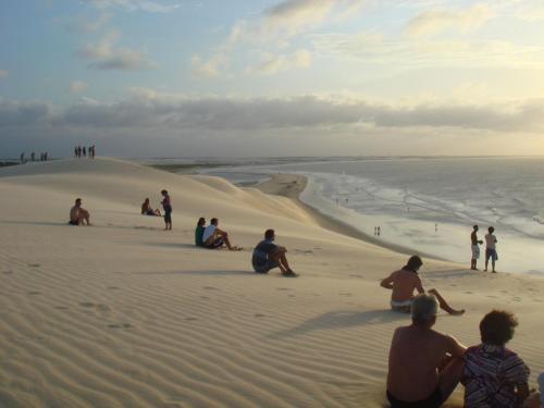people sitting on the sand at the beach at Pousada Caminho da Praia in Jericoacoara