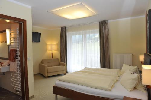 a bedroom with a bed and a chair and a window at Villa Castelli in Schladming
