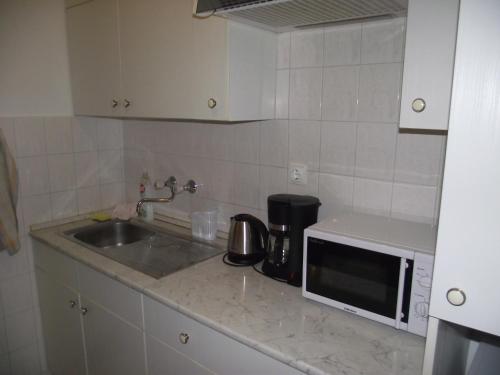 a kitchen with a sink and a microwave at Apartman Kaszás City in Mosonmagyaróvár