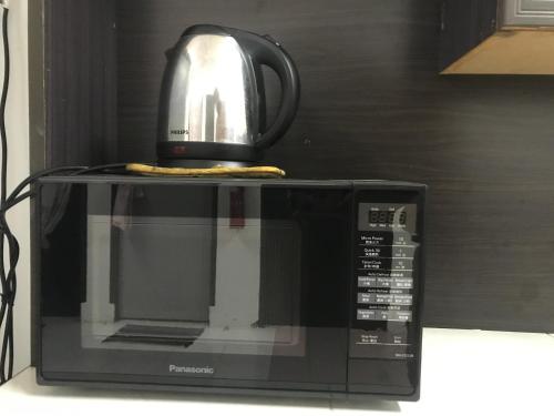 a microwave with a tea kettle on top of it at Seri Manjung Homestay Wazer Residence in Lumut