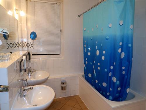uma casa de banho com 2 lavatórios e uma cortina de chuveiro azul em Hotel Adler Leipzig em Leipzig