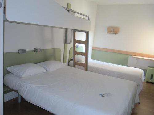 a bedroom with two bunk beds with white sheets at IBIS Budget Pontivy in Pontivy
