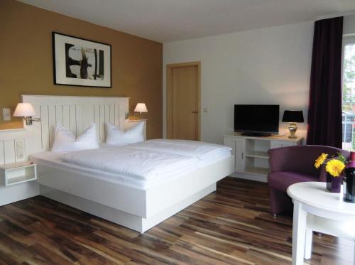 a bedroom with a white bed and a purple chair at Pension Delia Will in Ahlbeck