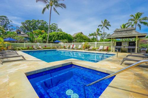 a swimming pool in a yard with palm trees at Sandpiper #116b in Princeville
