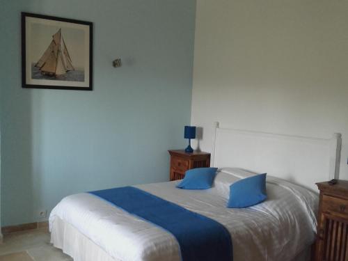 a bedroom with a bed with blue pillows on it at La Bastide de l'Oliveraie in Le Castellet