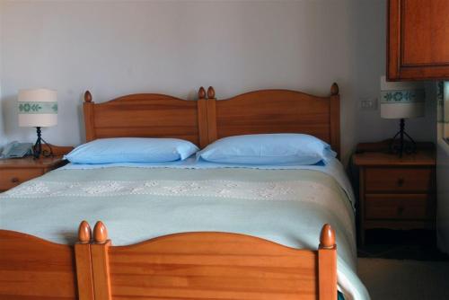 a bedroom with a wooden bed with blue pillows at Hotel Su Nuraxi in Barùmini