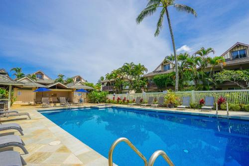 a swimming pool in a villa with a palm tree at Sandpiper #116b in Princeville