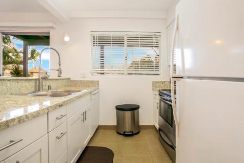 a kitchen with white cabinets and a refrigerator at SandPiper #116a in Princeville