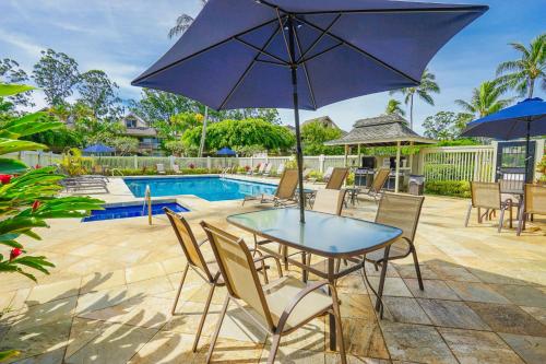 a patio with a table and chairs and an umbrella at Sandpiper #116b in Princeville