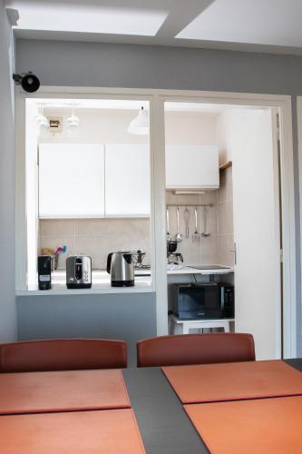 una cocina con armarios blancos y una mesa con sillas. en Charmant séjour au coeur du Touquet en Le Touquet-Paris-Plage
