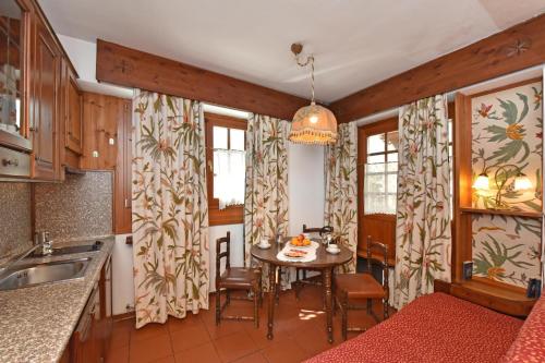 eine Küche mit einem Tisch, Stühlen und Fenstern in der Unterkunft Residence Castelli in Breuil-Cervinia