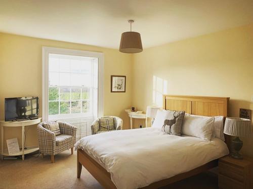a bedroom with a bed and a tv and a window at Lanercost Country B&B in Brampton