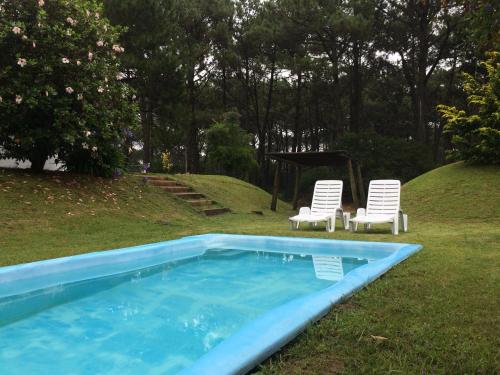 a swimming pool with two chairs and a table and two chairs at Casa Dash Beach Houses in Punta del Este