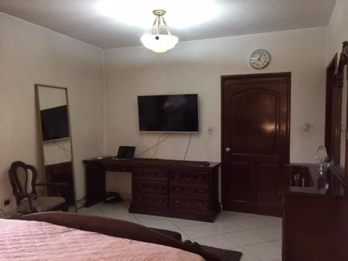 a bedroom with a bed and a dresser and a television at Apartamentos Comodos Cerca del Aeropuerto in Guatemala
