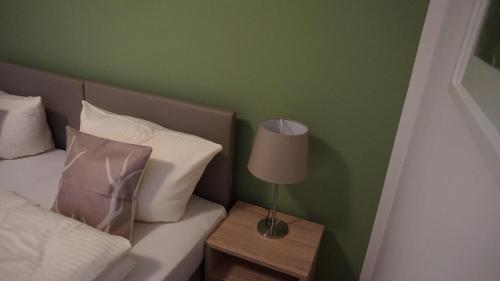 a bed with white pillows and a lamp on a table at Pension Turm in Schönwald