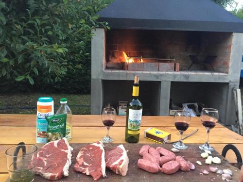 - une table avec deux verres de vin et de la viande dans l'établissement The Old Viking Fly Fishing- Alojamiento, à Junín de los Andes