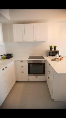 a kitchen with white cabinets and a stove top oven at Suite Caesar - Neot Golf in Caesarea