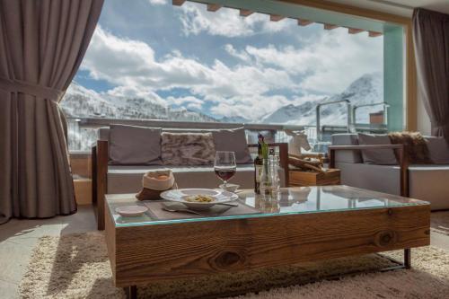 a living room with a table with a wine glass at White Angel Hotel in Breuil-Cervinia