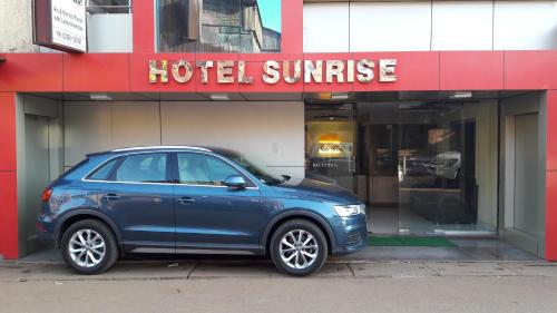 a blue car parked in front of a hotel sunrise at Hotel Sunrise in Mahabaleshwar