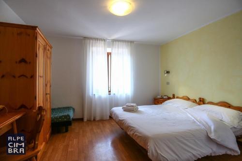 a bedroom with a large bed and a window at CASA MIFEL -- APP. GERANIO in Folgaria