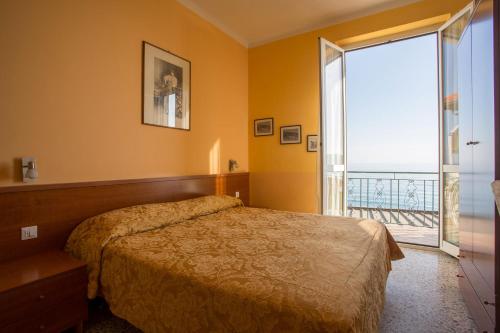 a bedroom with a bed and a large window at Hotel Badano sul Mare in Alassio