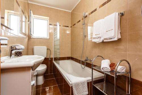 a bathroom with a tub and a toilet and a sink at Mare & Mons Seafront Apartments in Malinska