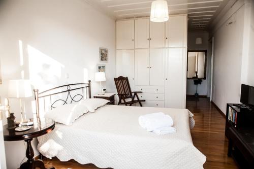 a bedroom with a white bed and a chair at La Casa di Caterina in Lefkada