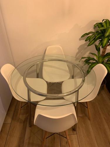 a glass table with four white chairs and a plant at Apartamento situado a 10 minutos de opera in Madrid