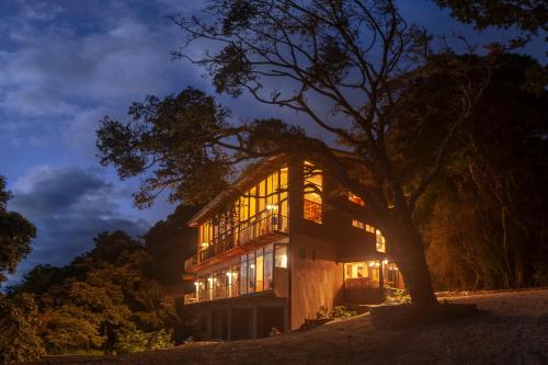 ein nachts beleuchtetes Haus mit einem Baum in der Unterkunft Koora Monteverde-a Cloud Forest Hotel by Sandglass in Monteverde Costa Rica