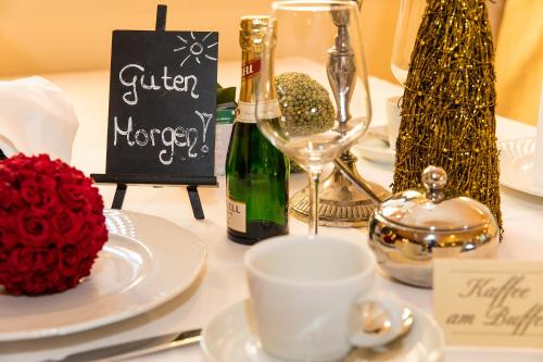 a table topped with white plates and a bottle of champagne at Hotel Garni Pölzl in Deutschlandsberg