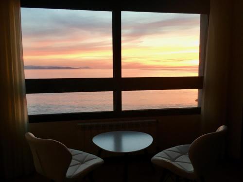 a view of the ocean from a window with a table and chairs at Hostal Casa Aurita Adults Only in Sanxenxo