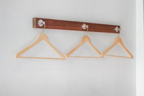 a wooden rack with four hangers on a wall at Mimi and Jim Co-living space in Cha Am