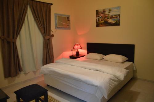 a bedroom with a bed with a lamp and a window at Zahrt Nadeen in Tabuk
