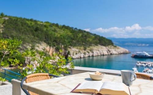 a table with an open book and a cup of coffee and a book at Seafront Apartment With Amazing Seaview in Vrbnik