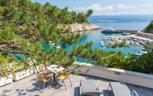 a view of a harbor with chairs and boats in the water at Seafront Apartment With Amazing Seaview in Vrbnik
