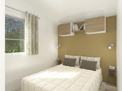 - une chambre avec un grand lit blanc et une fenêtre dans l'établissement Camping de Loperhet, à Plouharnel