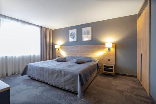a bedroom with a large bed and two lamps at Favor Park Hotel in Kyiv