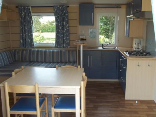 a kitchen and living room in a caravan with a table and chairs at Camping Paradis Les Galets de la Molliere in Cayeux-sur-Mer