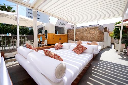 białą kanapę siedzącą pod pergolą na patio w obiekcie Fénix Torremolinos - Adults Only Recommended w mieście Torremolinos