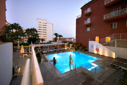 a woman is standing in a swimming pool next to a building at Fénix Torremolinos - Adults Only Recommended in Torremolinos
