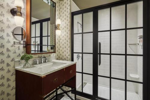 a bathroom with a sink, mirror and bath tub at Graduate Bloomington in Bloomington