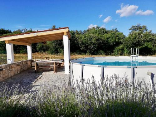 a swimming pool with a pavilion and a picnic table at Guesthouse Katica in Barban