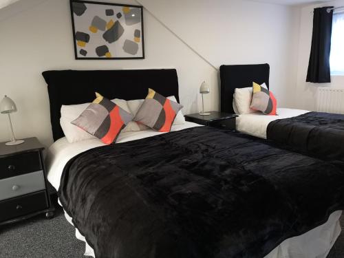 a hotel room with two beds and two nightstands at Havering Guest House in Romford
