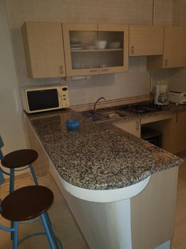 a kitchen with a granite counter top and two bar stools at L'appartement bleu de la Marsa in La Marsa
